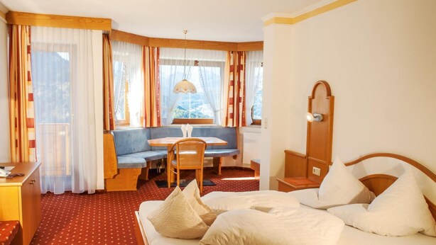 Una habitación de hotel con una cama, un escritorio, una silla y una ventana con cortinas.