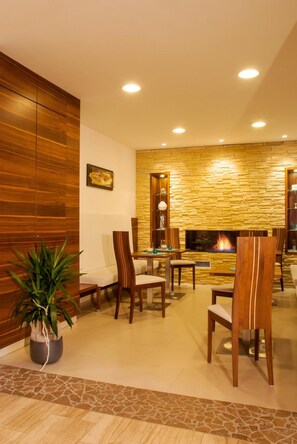 A modern living room with a stone wall, a fireplace, and wooden furniture. - Pension Romantica (Jerzens)