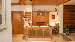 Una cocina con armarios de madera, una isla central, un comedor con mesa y sillas, y una planta en maceta.
