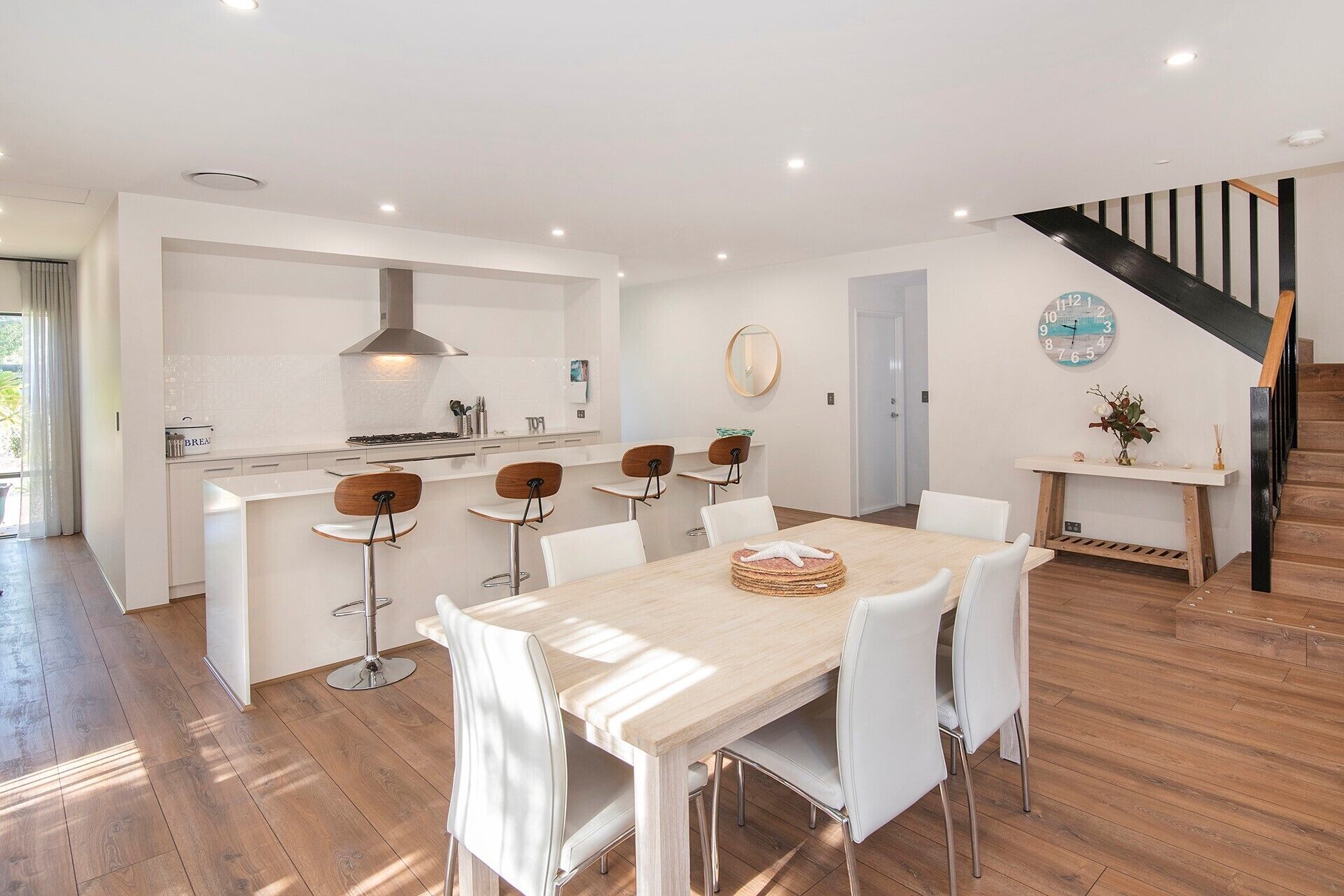 A modern kitchen with white cabinetry, a central island, and bar stools.