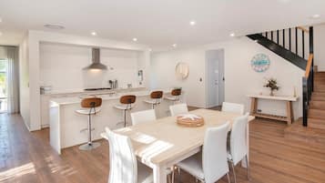 A modern kitchen with white cabinetry, a central island, and bar stools.