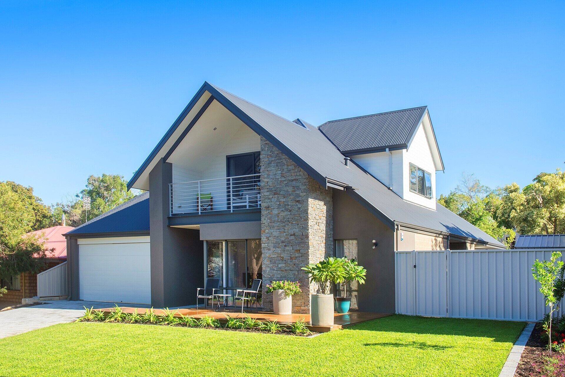 A modern two-story house with a balcony, a garage, and a well-maintained lawn.
