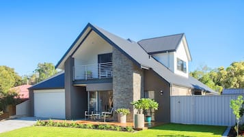 A modern two-story house with a balcony, a garage, and a well-maintained lawn.