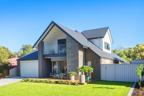 A modern two-story house with a balcony, a garage, and a well-maintained lawn. - The Milly (Dunsborough)