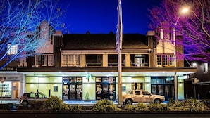 A building with a flagpole, a parked car, and a street lamp.