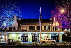 Un edificio con un asta de banderín, un coche estacionado y una farola.