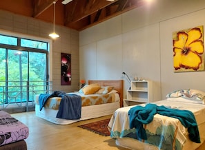 Une chambre avec deux lits, une grande fenêtre et une œuvre d’art accrochée au mur.