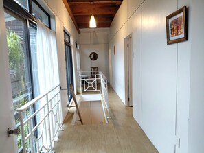A hallway with a wooden ceiling, a white railing, and a door on the right. - Spacious 3-Bedroom Boutique Villa for Families (Rarotonga)