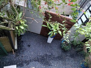Ein Dachgarten mit Topfpflanzen, einem Holzzaun und einer Kiesfläche.