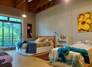 Una camera da letto con due letti, un'ampia finestra e una parete con un quadro.