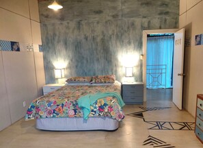 A bedroom with a bed, bedside tables, a wardrobe, and a door leading to another room. - Spacious 3-Bedroom Boutique Villa for Families (Rarotonga)