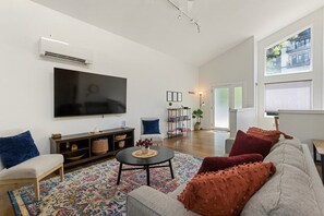 A modern living room with a flat-screen TV, a sofa, a coffee table, and a patterned rug. - Hamilton Villa | Modern Retreat | Walk to Town! (Chattanooga)
