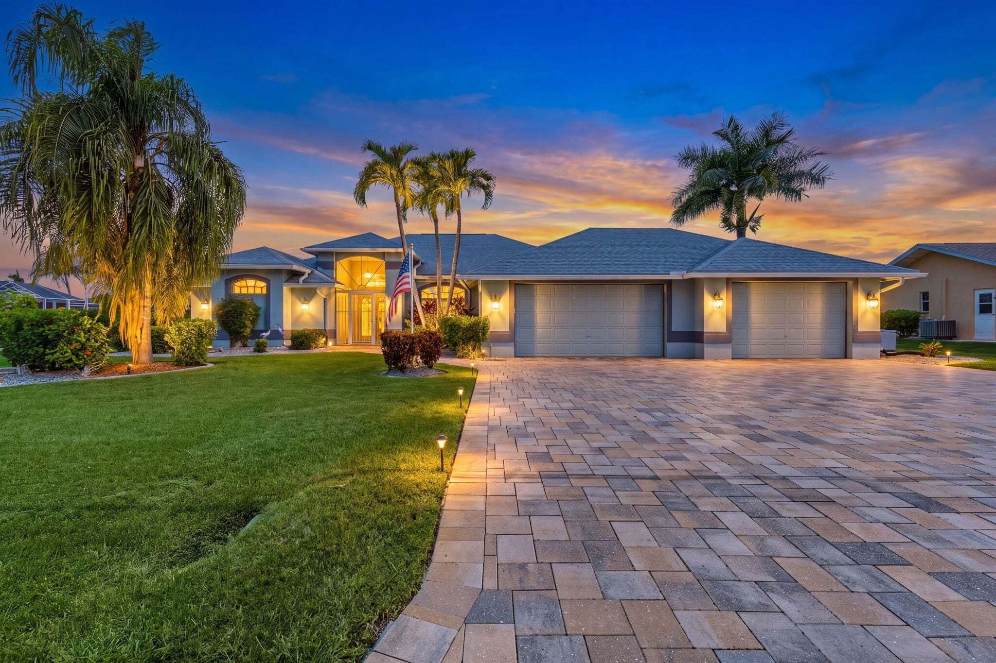 A residential property with a paved driveway, well-maintained lawn, and multiple garage doors.