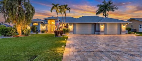 A residential property with a paved driveway, well-maintained lawn, and multiple garage doors.
