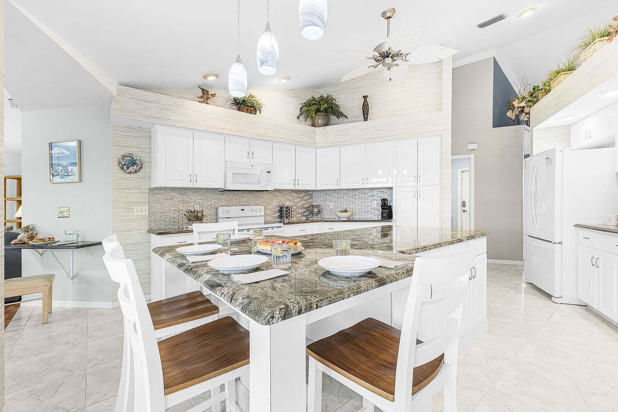 A modern kitchen with white cabinetry, a granite island, and pendant lighting.