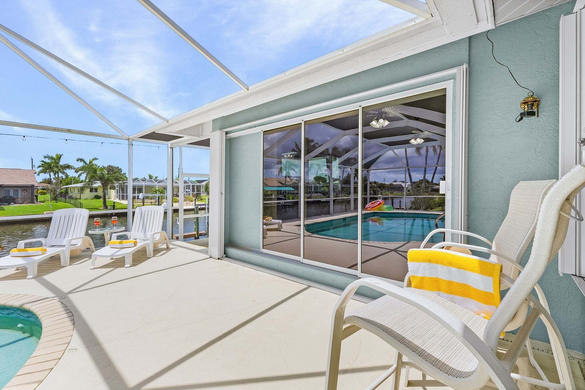 A covered outdoor area with a pool, lounge chairs, and a view of the surrounding landscape.