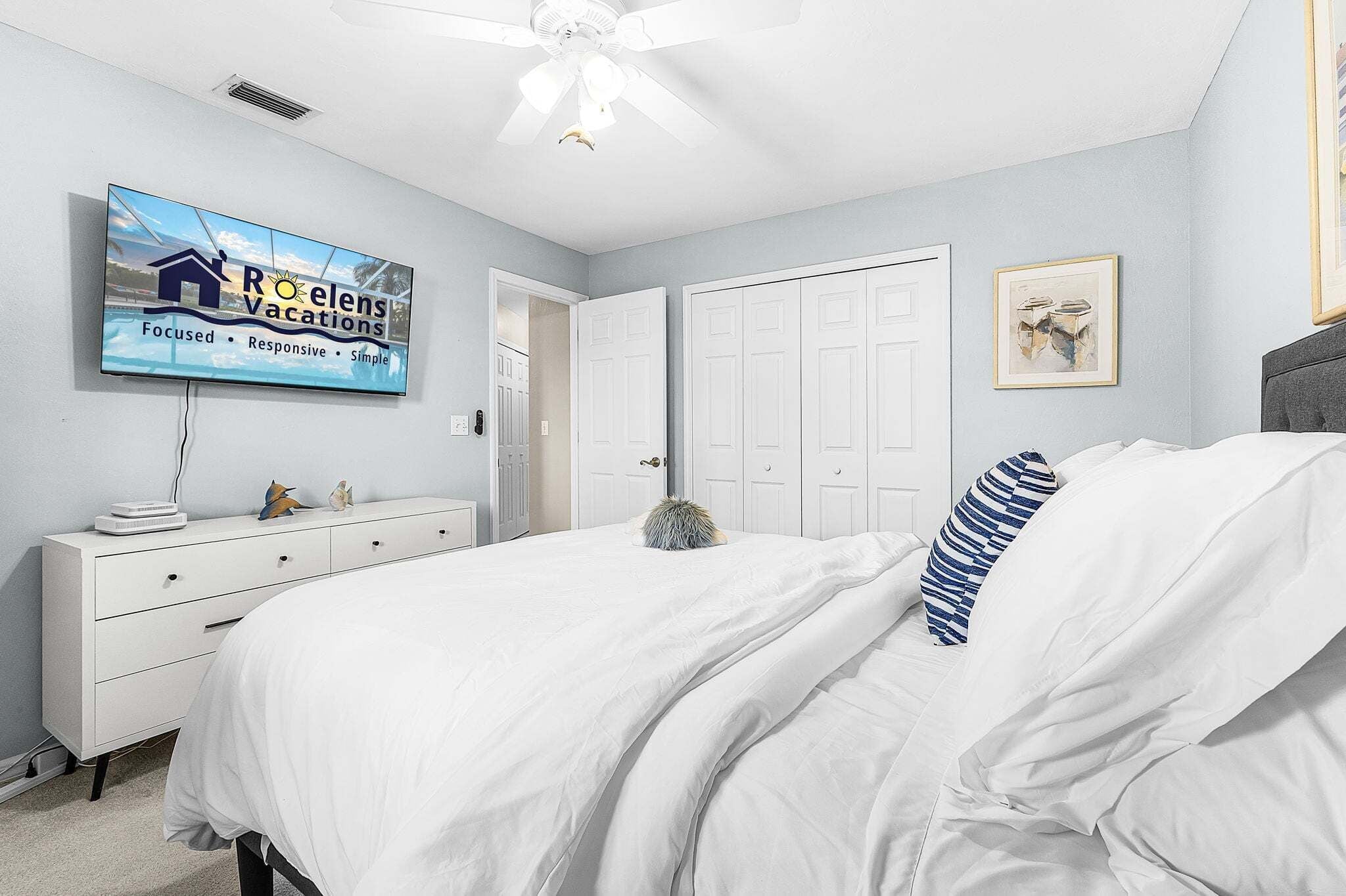 Un dormitorio con cama, cómoda, televisor y puerta.