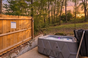 Ein Whirlpool mit Holzzaun und einem Schild, umgeben von Bäumen und einem Sonnenuntergang.