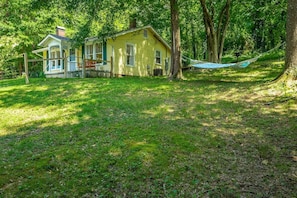 A yellow house with a porch, surrounded by trees and grass. - Lucky's Cottage | Hot Tub+Dog Friendly+Fire Pit (Rossville)