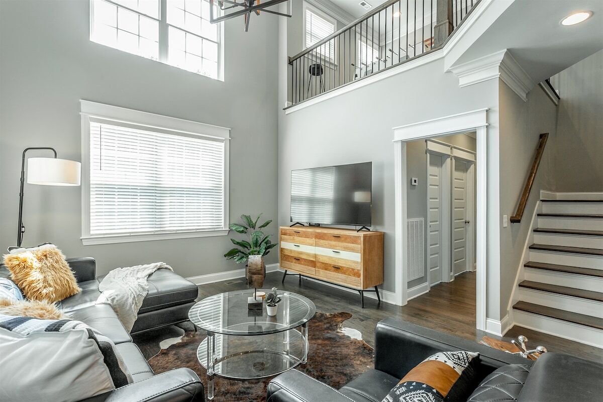 A spacious living room with a modern sofa, a glass coffee table, and a television.