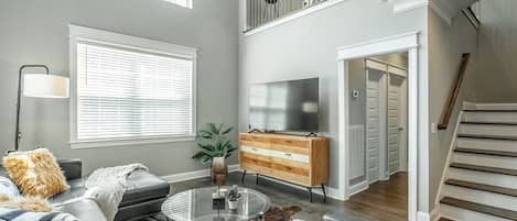 A spacious living room with a modern sofa, a glass coffee table, and a television.