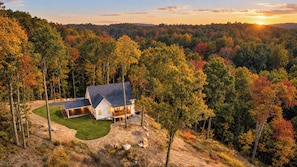 Une maison entourée d’une forêt, sous un ciel dégagé.