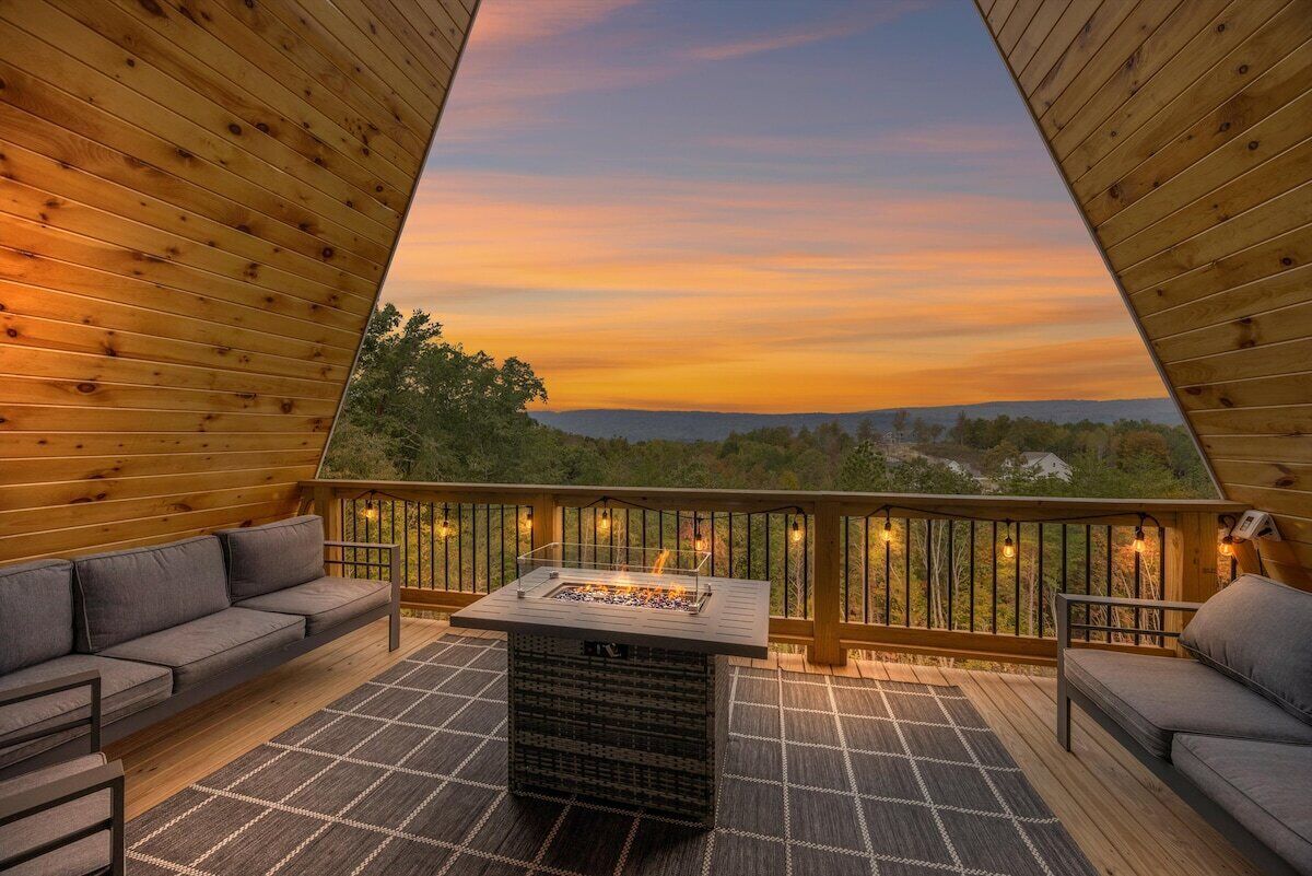 An outdoor deck with a fire feature, seating, and a view of the landscape.
