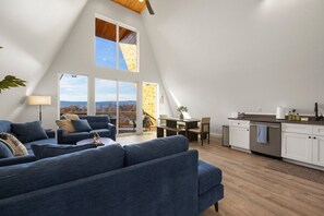 A spacious loft with a high ceiling, a dining area, and a kitchen with a view of the outdoors. - Urban Vista | A-Frame | Theatre + Pet Baby Goats! (Rossville)