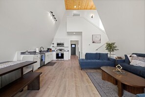 A modern interior with a kitchen, dining area, and living room. - Urban Vista | A-Frame | Theatre + Pet Baby Goats! (Rossville)