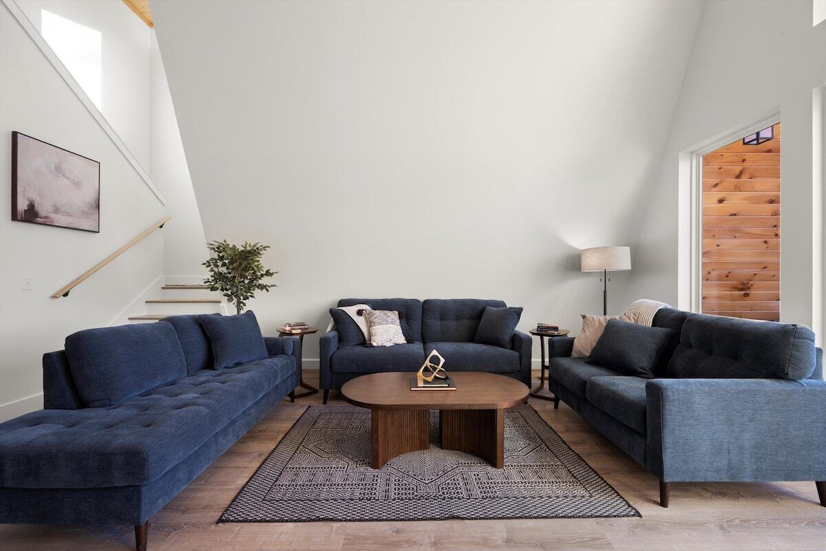 A modern living room with a dark blue sofa set, a round coffee table, and a floor lamp.