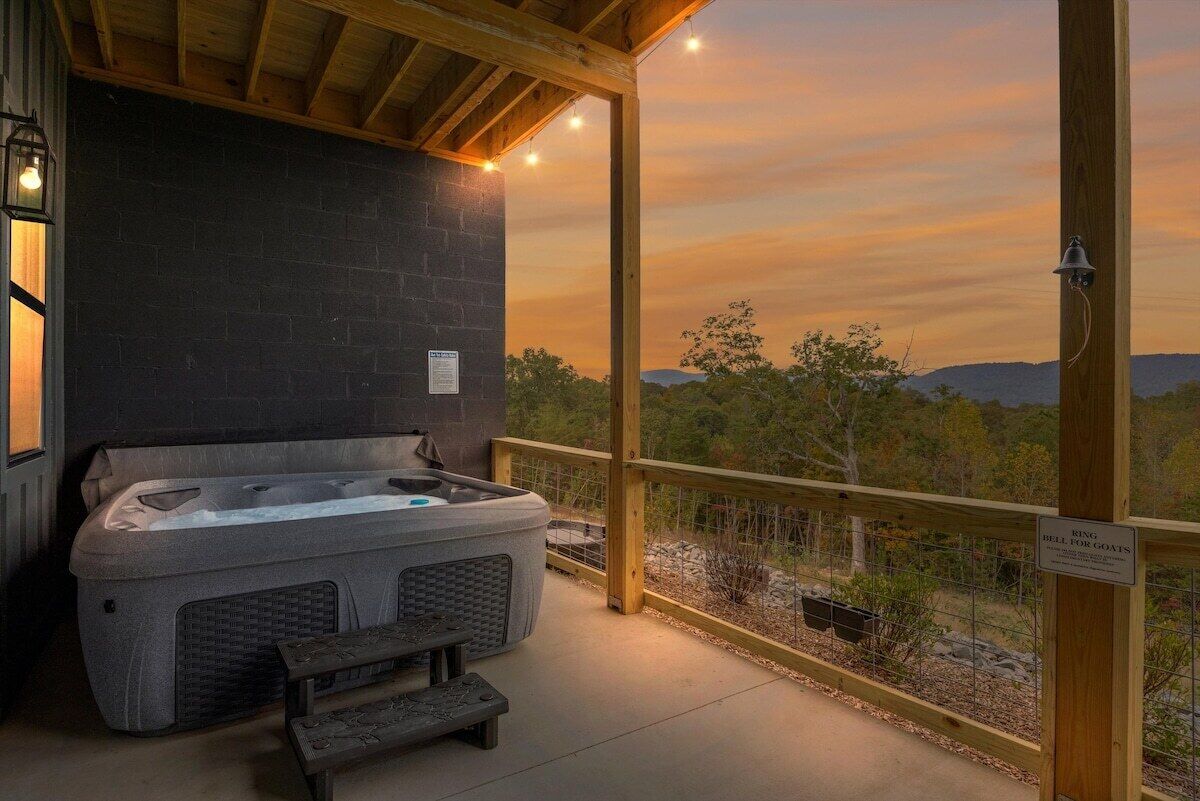 Un jacuzzi con un banco de madera, una pared de ladrillo y vistas a árboles y montañas.