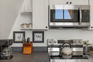 Eine moderne Küche mit Mikrowelle, Backofen und Kaffeemaschine aus Edelstahl.