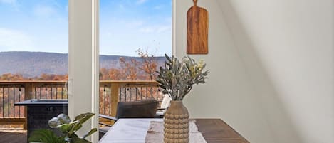 A dining area with a table, a vase, and a view of the outdoors.