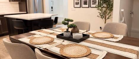 A dining area with a wooden table, woven placemats, and a small potted plant.