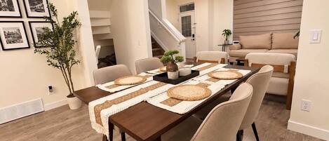 Un espace repas avec une longue table, des chaises et un escalier en arrière-plan.