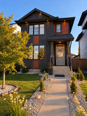A modern two-story house with a front entrance, a well-maintained lawn, and a pathway leading to the door. - Family-Friendly 5BR Home| Basement Included (Edmonton)