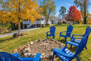 A backyard with a fire pit, blue Adirondack chairs, and a house in the background. - 2 Apartments with Country Views | Dog Friendly! (Rossville)