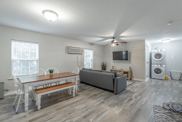 A modern living room with a dining table, sofa, and a ceiling fan. - 2 Apartments with Country Views | Dog Friendly! (Rossville)
