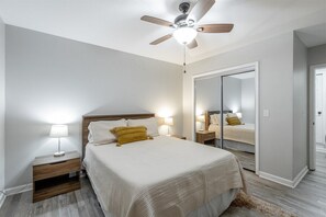 A bedroom with a bed, bedside lamps, a ceiling fan, a wardrobe, and a mirror. - 2 Apartments with Country Views | Dog Friendly! (Rossville)