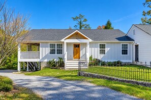 A single-story house with a front porch, a stone wall, and a fenced yard. - 2 Apartments with Country Views | Dog Friendly! (Rossville)