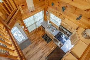 Ein Interieur einer Holzhütte mit Küche, Holzwänden, einem Fenster und einer Treppe.