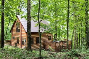 Eine Holzhütte mit Terrasse, umgeben von dichtem Wald.