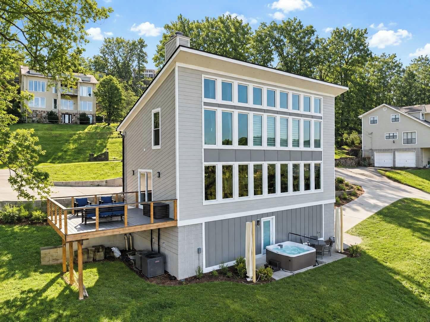 Ein modernes, zweistöckiges Haus mit Terrasse, Whirlpool und gepflegtem Rasen.