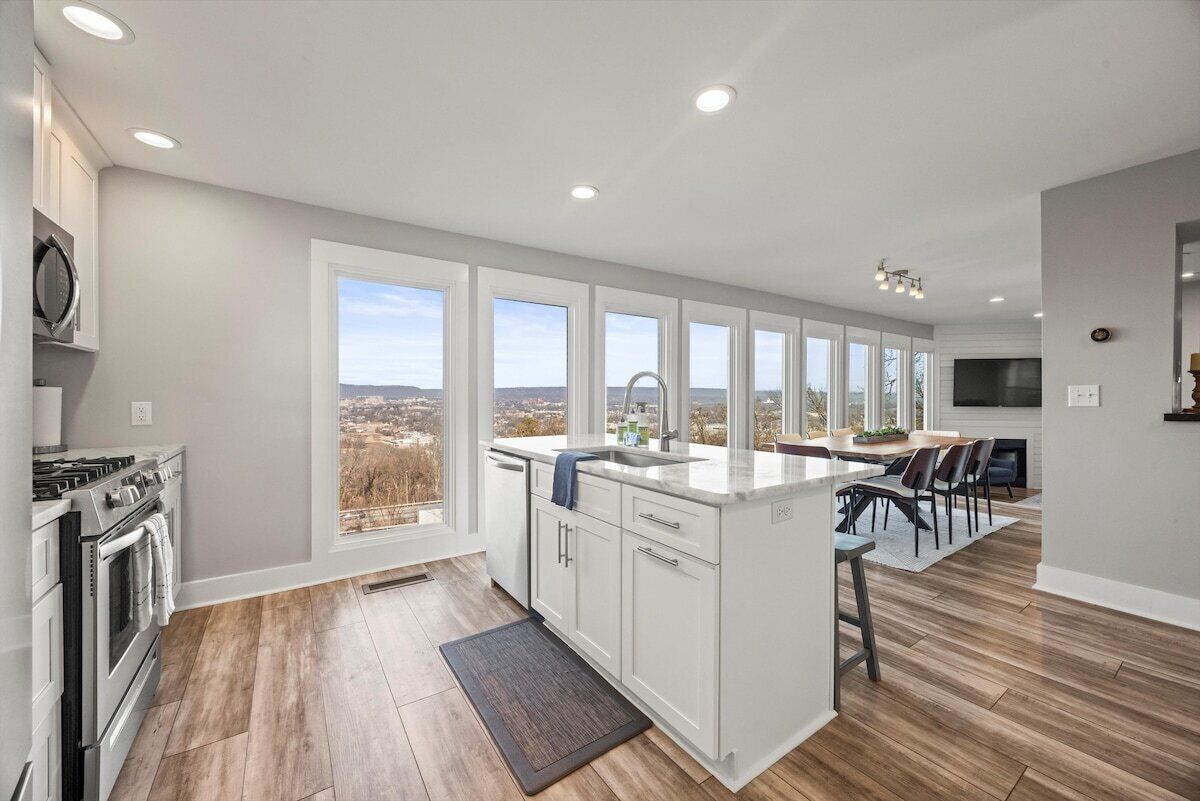 Una cocina moderna con una isla grande, muebles blancos y vistas a la ciudad.