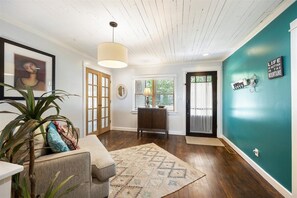 Un intérieur moderne avec un mur d’accent de couleur turquoise, un plancher en bois, un tapis à motifs et un coin salon confortable agrémenté d’une plante.