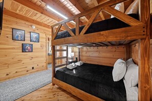 A bunk bed room with wooden walls, a gray rug, and framed pictures on the wall. - Crossbow Cabin | Lookout Mountain • Stunning Views (Rising Fawn)