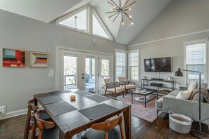A spacious living room with a dining area, large windows, and a flat-screen TV. - Stellar View | North Shore Retreat | 30+ Nights (Chattanooga)