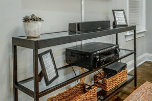 A glass-top console table with electronic equipment and baskets. - Stellar View | North Shore Retreat | 30+ Nights (Chattanooga)