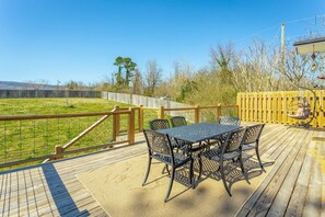 Eine Terrasse mit Tisch und Stühlen, mit Blick auf eine Rasenfläche.