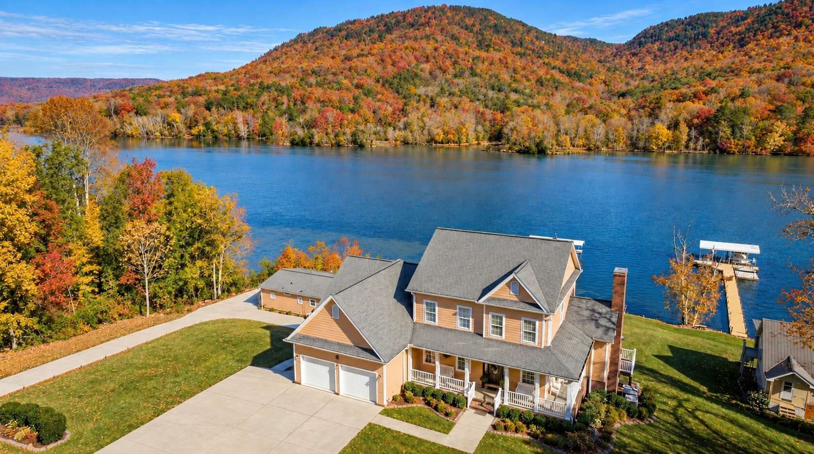 A two-story house with a garage, a dock, and a lake view.